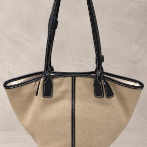 کیف دستی tote دنیم زغالی تیره با دسته‌های چرم مشکی و دوخت کنتراست سفید روی پس‌زمینه استودیویی مینیمال | Dark charcoal denim tote bag with black leather handles, white contrast stitching, displayed on a minimal beige studio background