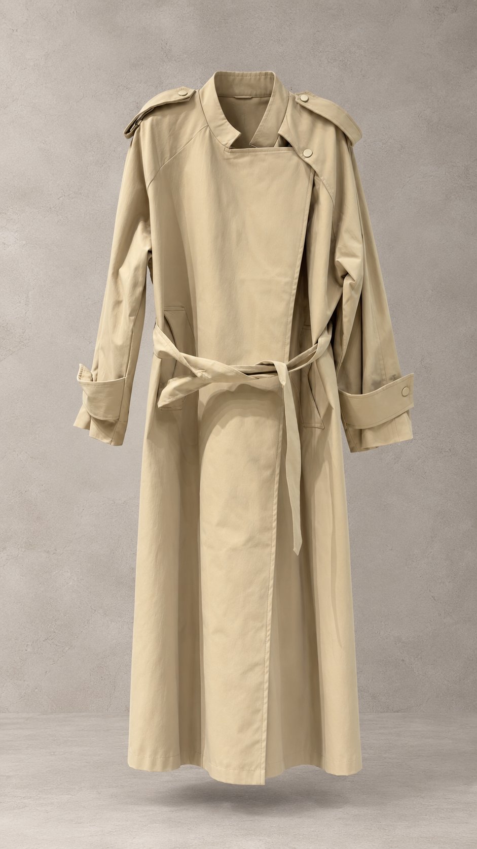 بارانی ترنچ‌کت بلند اورسایز زنانه با یقه ایستاده مدرن، کمربند پارچه‌ای و سرآستین‌های بنددار روی پس‌زمینه مینیمال استودیویی | Women’s minimalist oversized long trench coat with modern standing collar, fabric tie belt, and belted cuffs suspended against a studio backdrop