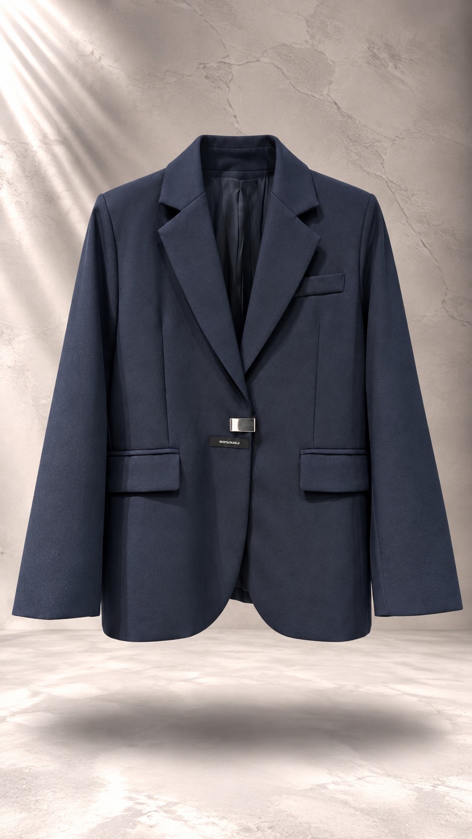 کت تک زنانه سرمه‌ای شیک با یقه انگلیسی و سگک فلزی مینیمال روی پس‌زمینه بتنی روشن | Tailored navy blue women’s blazer with modern metallic buckle closure floating against a minimal concrete background