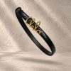 کمربند چرمی مشکی با سگک فلزی طلایی به فرم لوگوی تایپی برند Chloé در حال معلق | Black leather belt with gold-tone metal cursive Chloé logo buckle, floating in mid-air